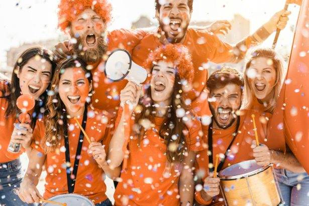 Orange sport fans screaming while supporting their team outside the stadium